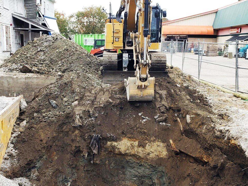 Excavator digging a deep excavation between commercial buildings