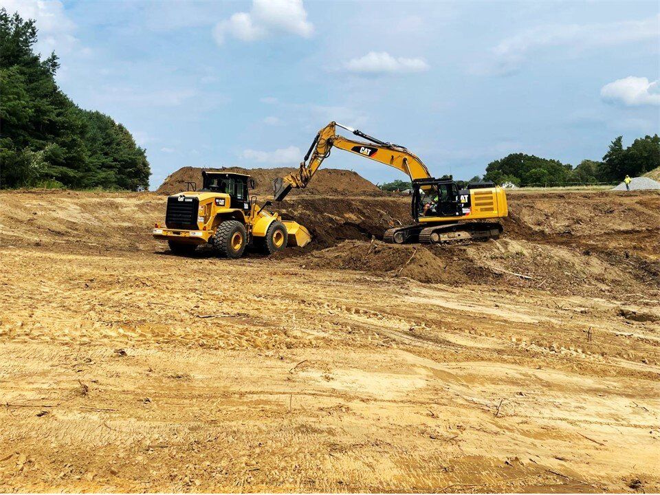 Excavator and wheel loader grading a large cleared site