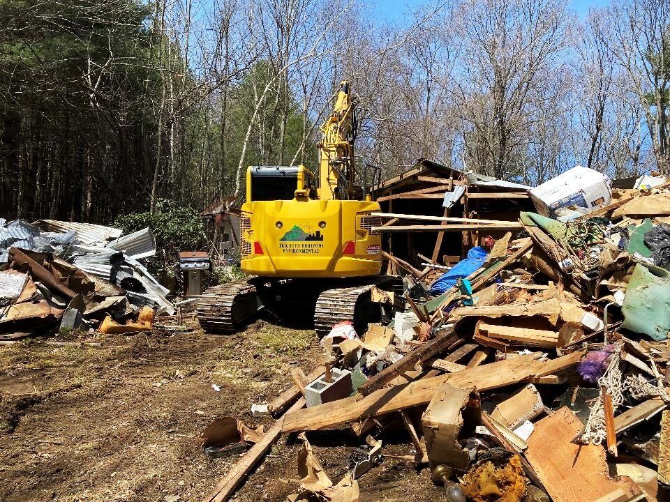 Excavator sorting timber and debris from a demolished structure