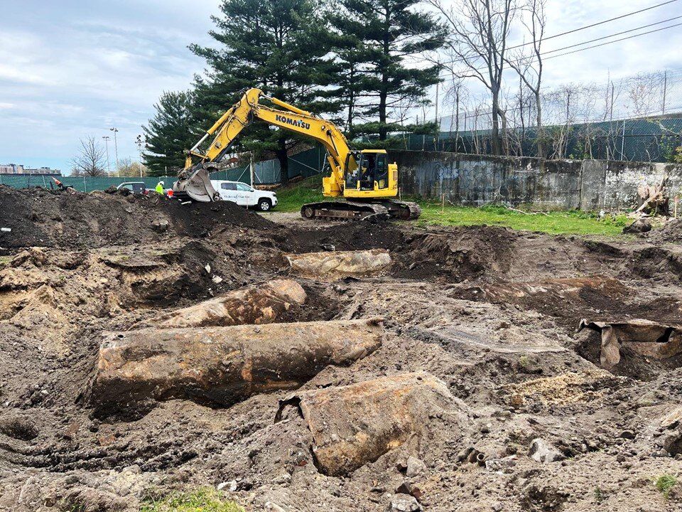 Excavator beside steel storage tanks unearthed during an excavation